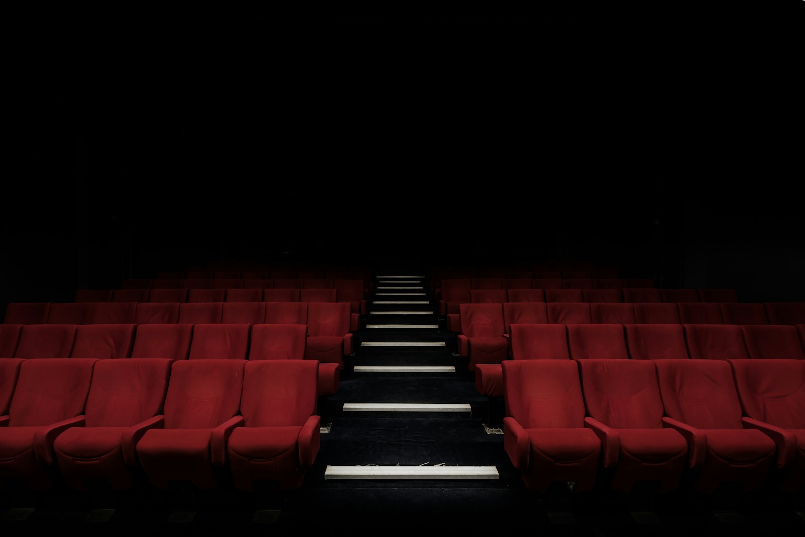 A dark, atmospheric cinema theater with glowing screen